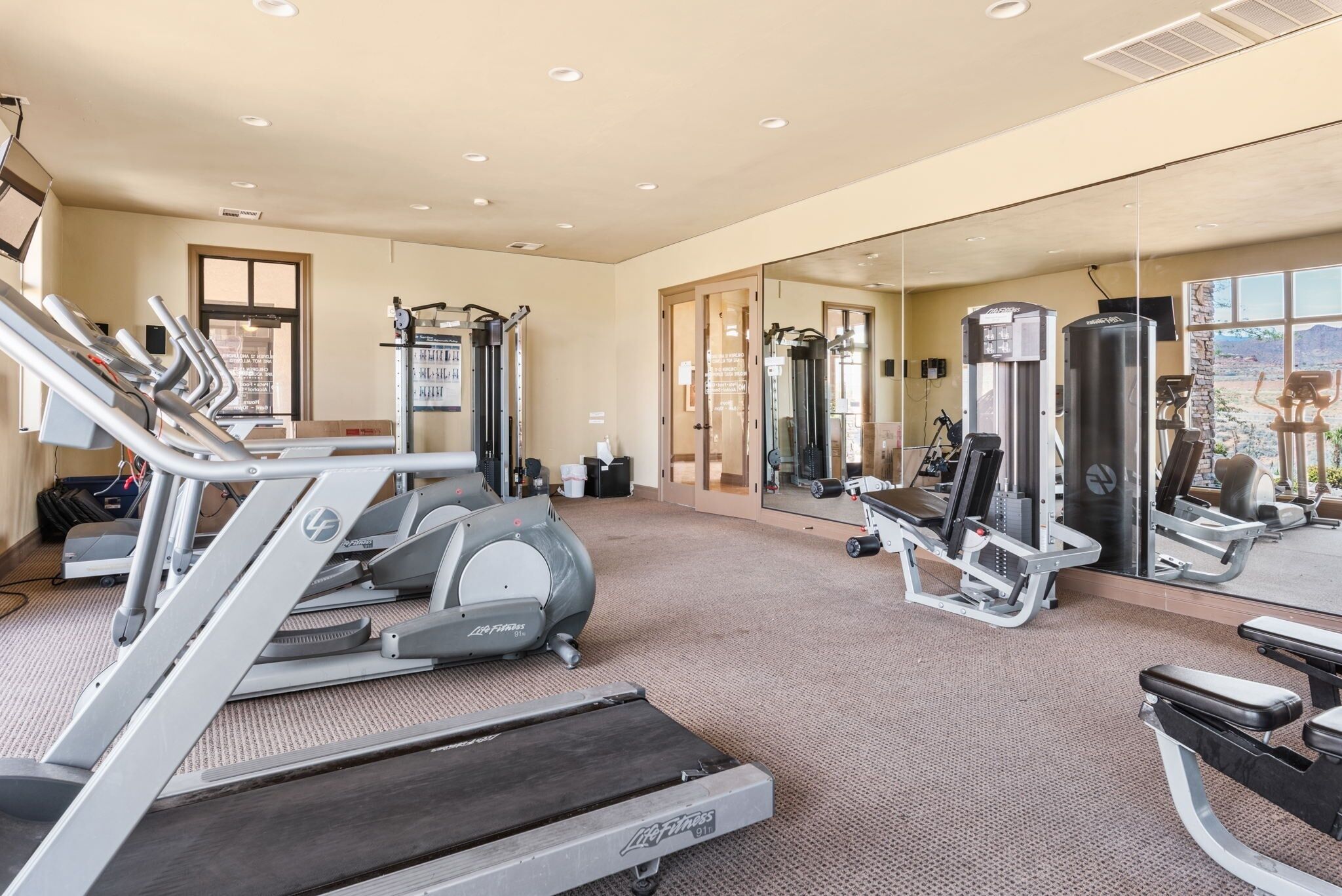 A gym with treadmills, weight machines, and a mirrored wall.