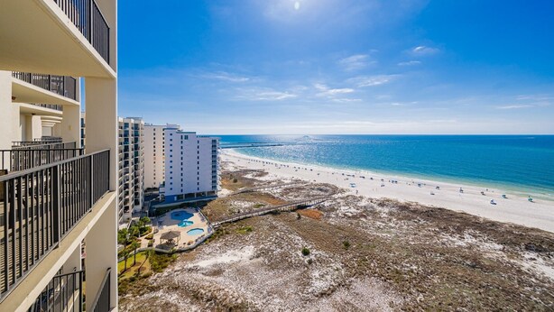 Hotel frente a la playa con varios balcones, piscina y vista al mar.
