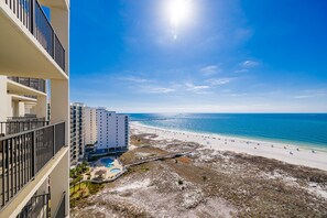 Hotel frente a la playa con varios balcones, piscina y vista al mar.