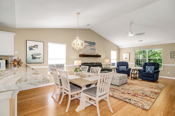 A spacious living area with a dining table, chairs, a sofa, and a ceiling fan.