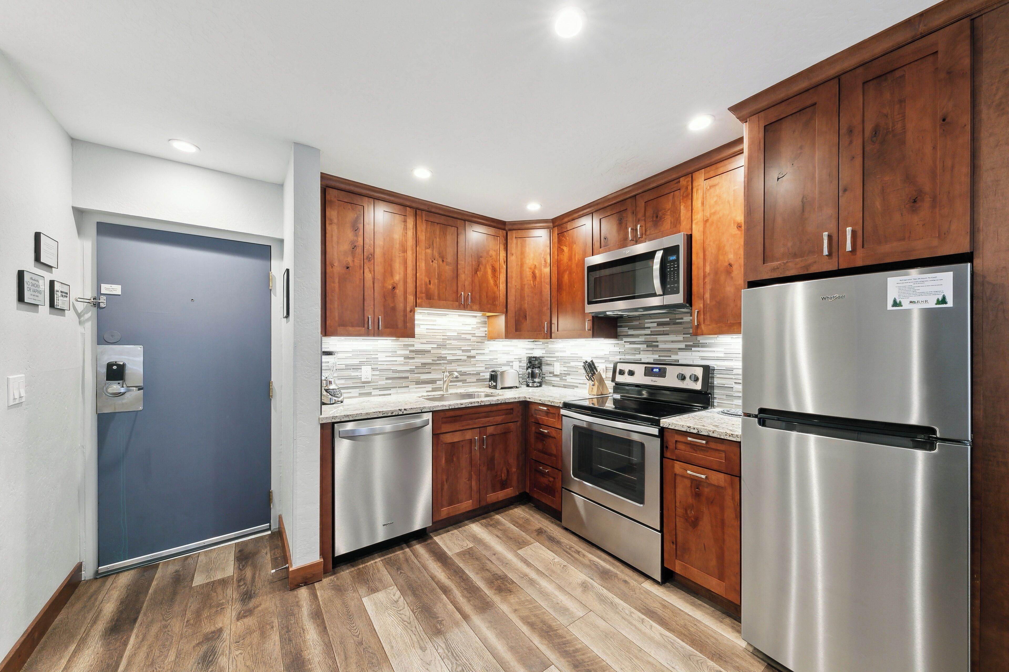 A modern kitchen with wooden cabinets, stainless steel appliances, and a tiled backsplash.
