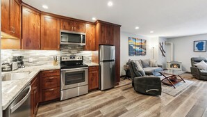 A modern kitchen with wooden cabinets, stainless steel appliances, and a marble countertop.