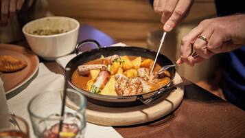 A person serving food from a pan on a wooden board.