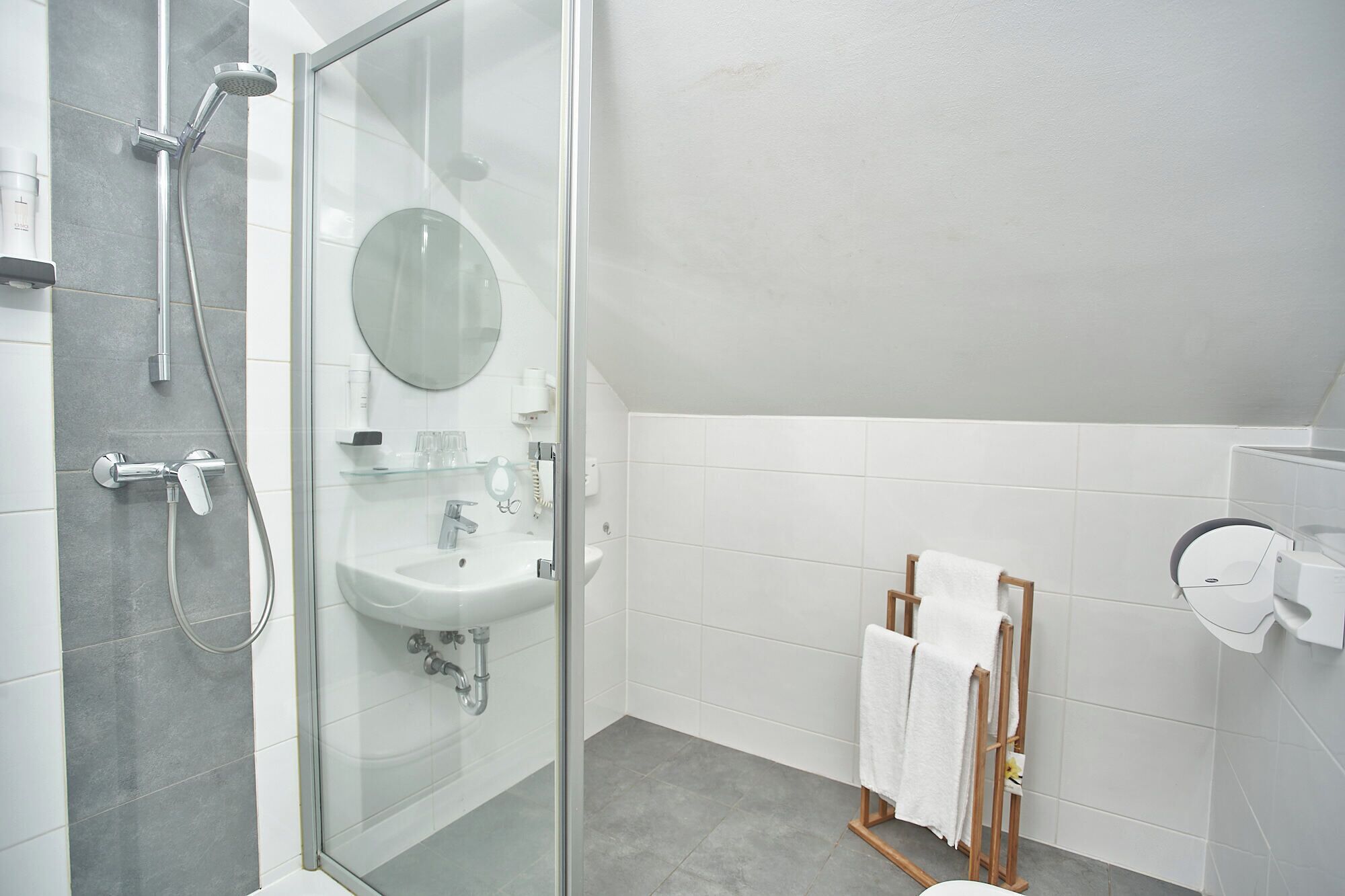 A modern bathroom with a glass shower enclosure, a sink with a mirror, and a towel rack.