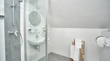 A modern bathroom with a glass shower enclosure, a sink with a mirror, and a towel rack.