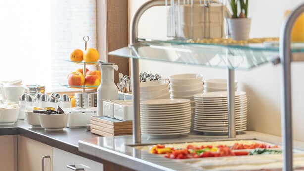 A buffet setup with multiple serving stations, including a glass display case and a variety of dishes. - Haus am See Stubenberg (Stubenberg)