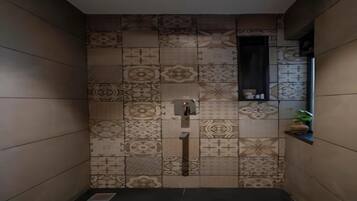 A bathroom with patterned tiles, a small window, and a shelf with toiletries.