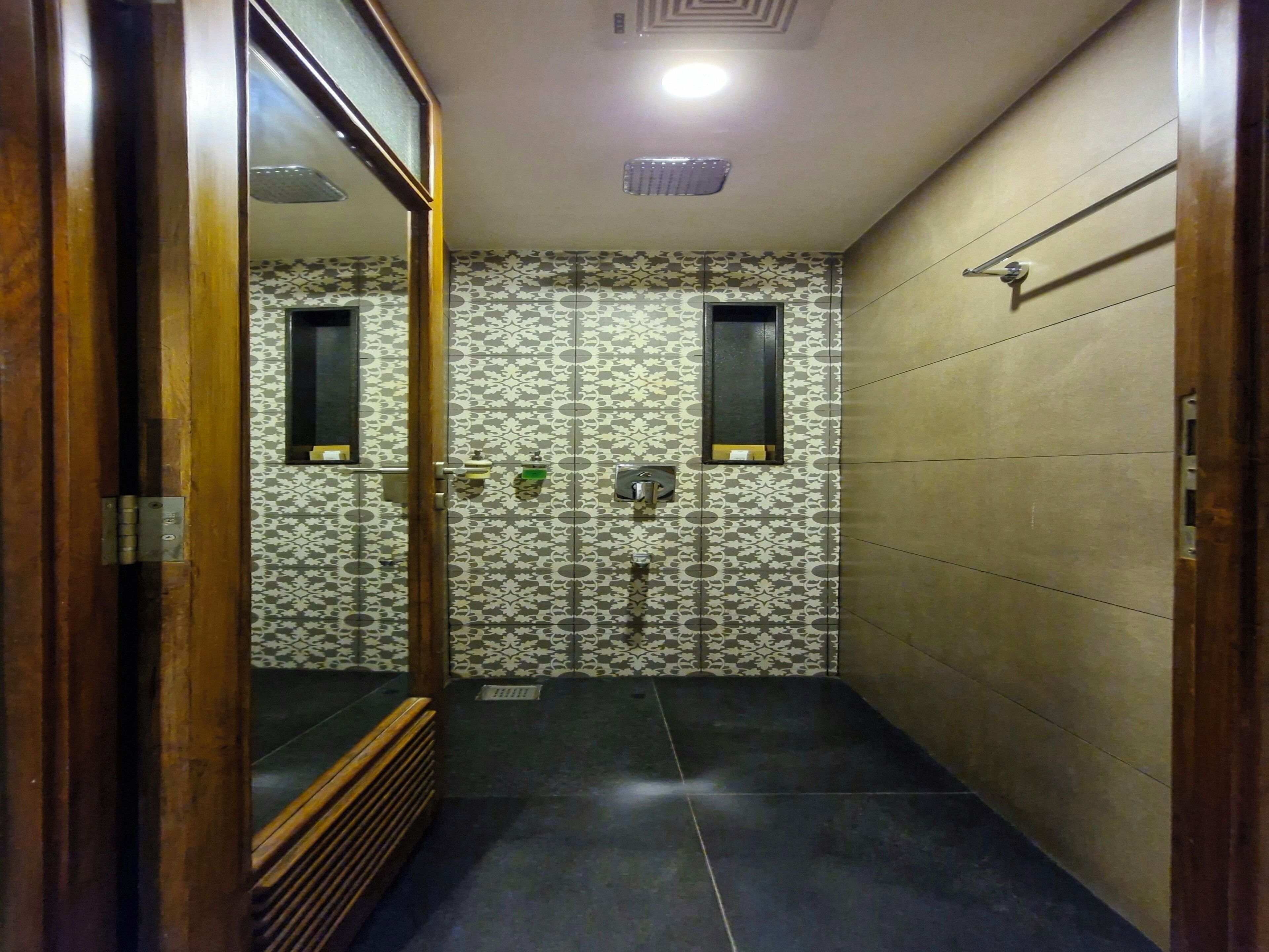 Un pasillo estrecho con paredes estampadas, un marco de puerta de madera y suelo de baldosas.