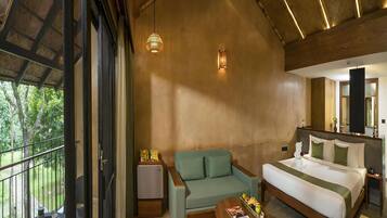 A modern hotel room with a balcony, a sofa, a bed, and a small table with fruits.