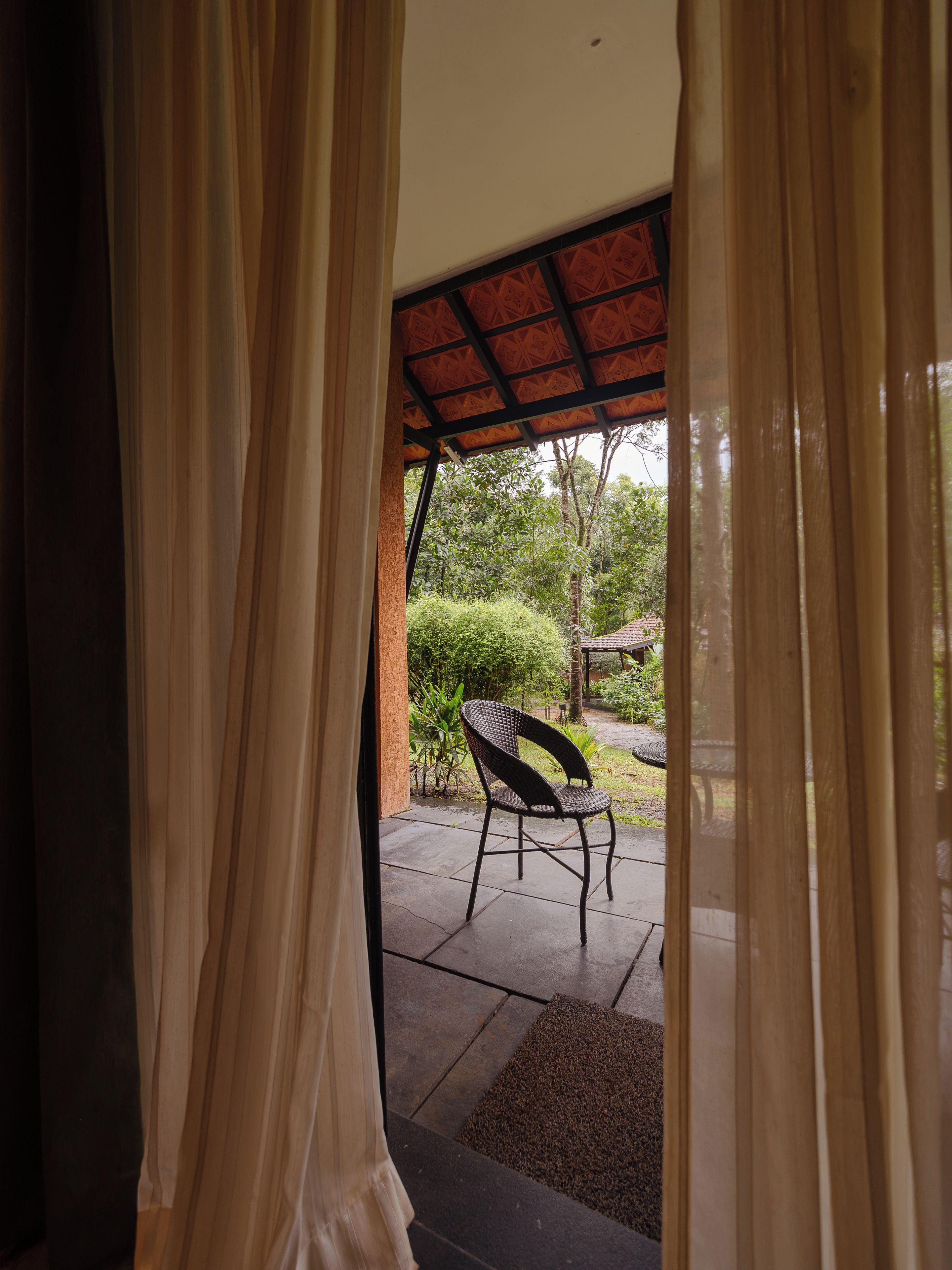 Una habitación con vistas a un área de estar exterior, una silla y un techo con diseño.