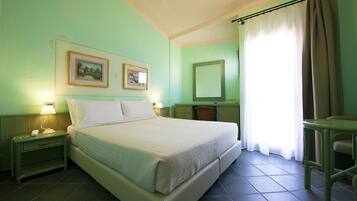 Una habitación con cama, mesitas de noche, escritorio, silla, espejo y dos cuadros en la pared.