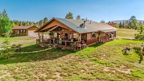 Une cabane en bois avec un porche couvert, un garage et une cour gazonnée.