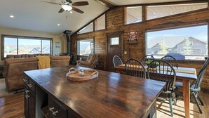 Une cuisine spacieuse avec un îlot central en bois, de grandes fenêtres et un ventilateur de plafond.