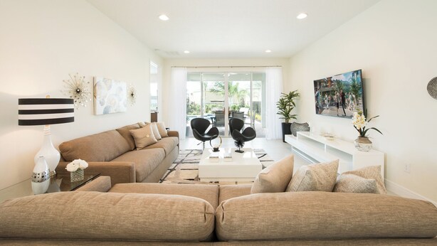 A modern living room with a sofa set, a coffee table, and a TV mounted on the wall. - Contemporary Disney VacationHome (Kissimmee)