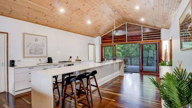 Una cocina moderna con una isla grande, taburetes de bar y vistas al exterior.