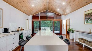 Una cocina moderna con una isla grande, techo de madera y ventanas amplias.