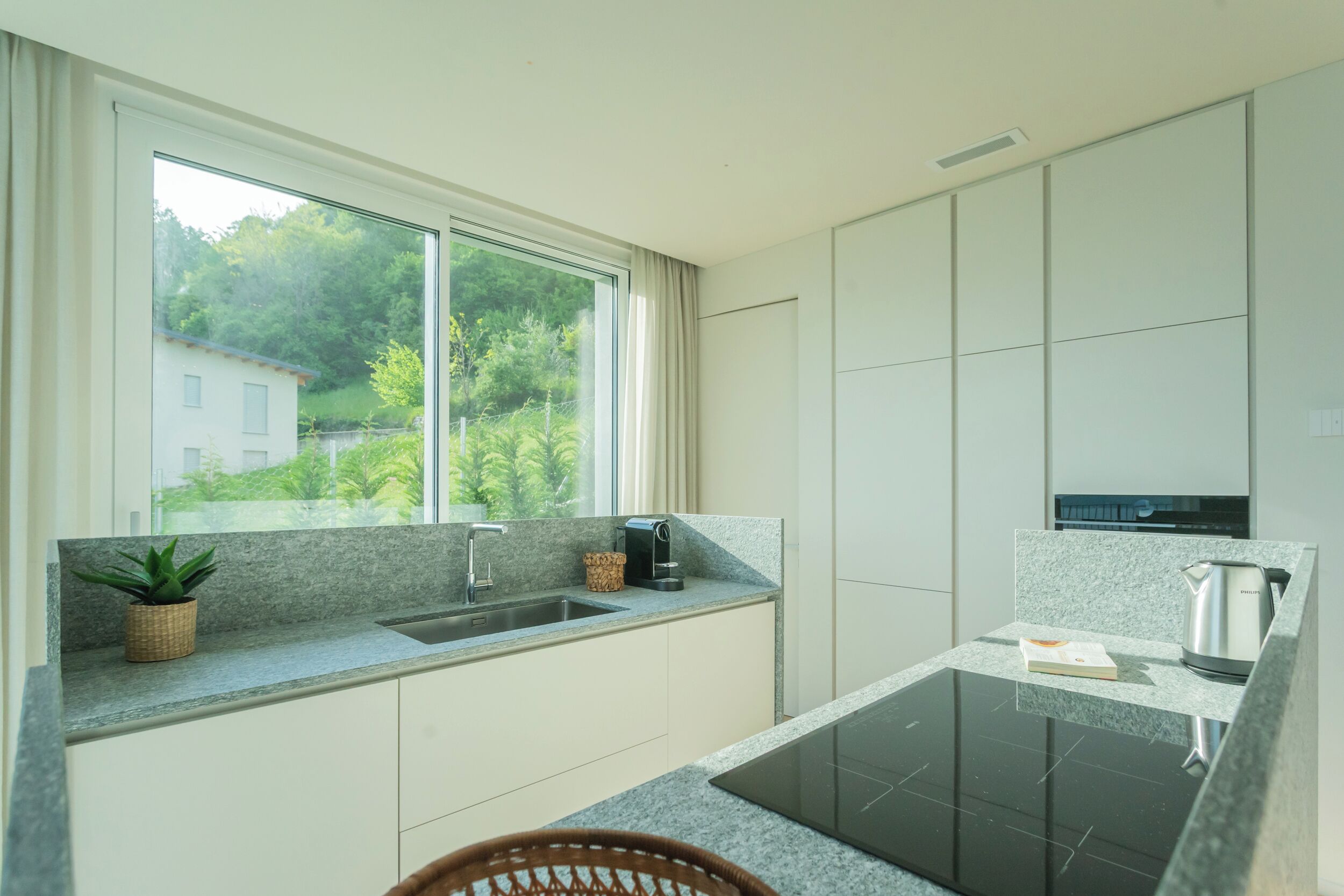 Una cocina moderna con un amplio ventanal, encimeras de granito y electrodomésticos integrados.