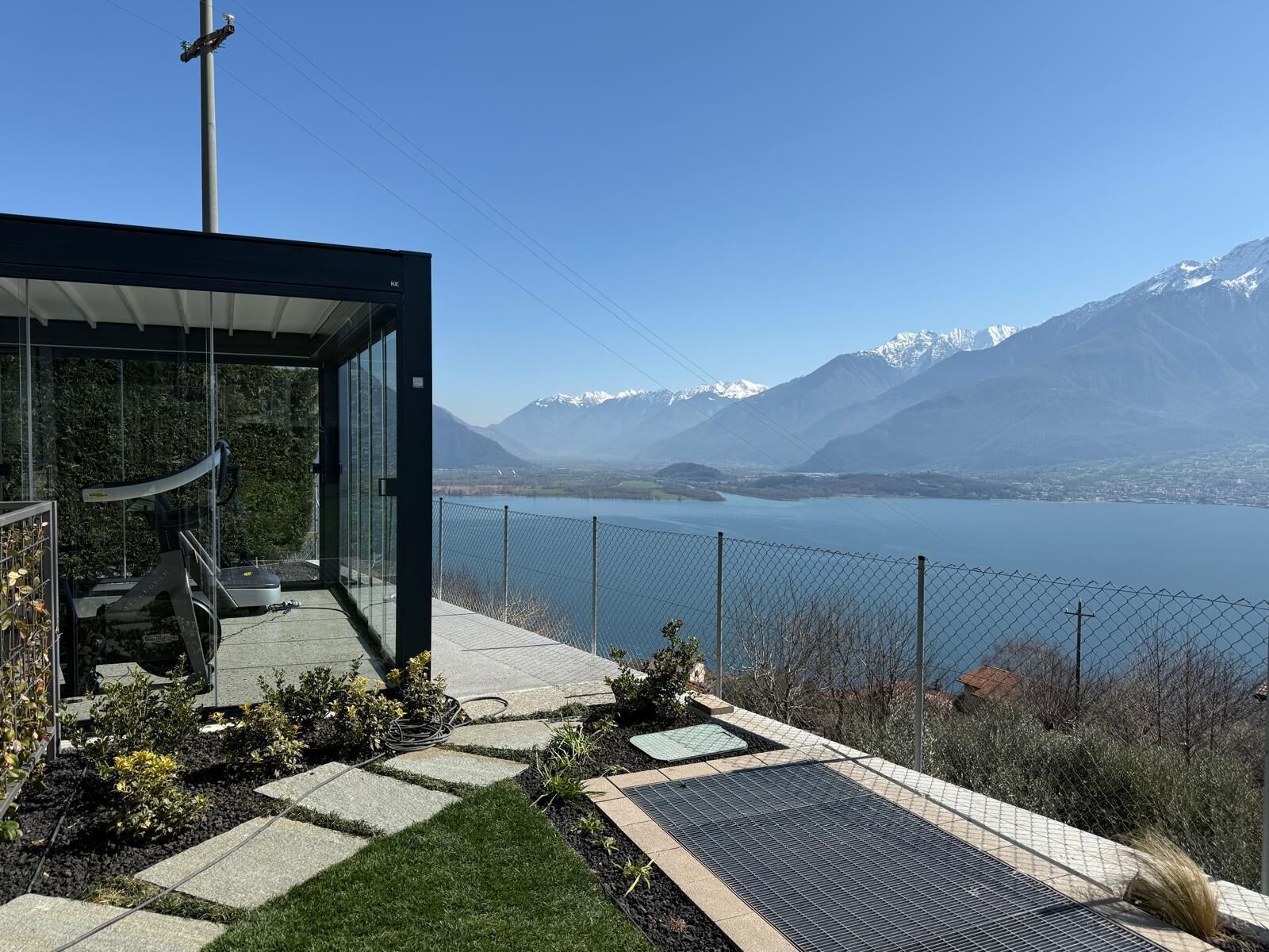 A modern glass structure with a view of a lake and mountains.
