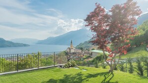 A scenic view of a lake with a church and residential buildings in the background. - Valarin Luxury Apartments & Wellness by Rent all Como (Vercana)