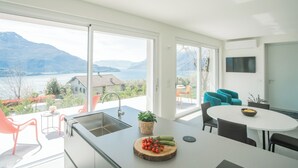 A modern kitchen with a large window, a sink, and a dining area with chairs. - Valarin Luxury Apartments & Wellness by Rent all Como (Vercana)
