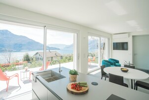 Una cocina moderna con un ventanal grande, un fregadero y un comedor con sillas.