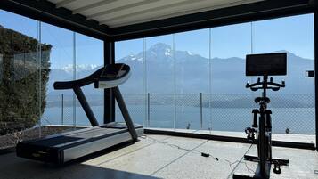 Et moderne fitnesscenter med løbebånd og motionscykel, store vinduer med udsigt til et bjergrigt landskab.