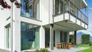 A modern two-story house with large windows, a balcony, and a well-maintained lawn.