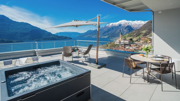 A rooftop terrace with a hot tub, outdoor seating, and a view of a lake and mountains. - Valarin Luxury Apartments & Wellness by Rent all Como (Vercana)