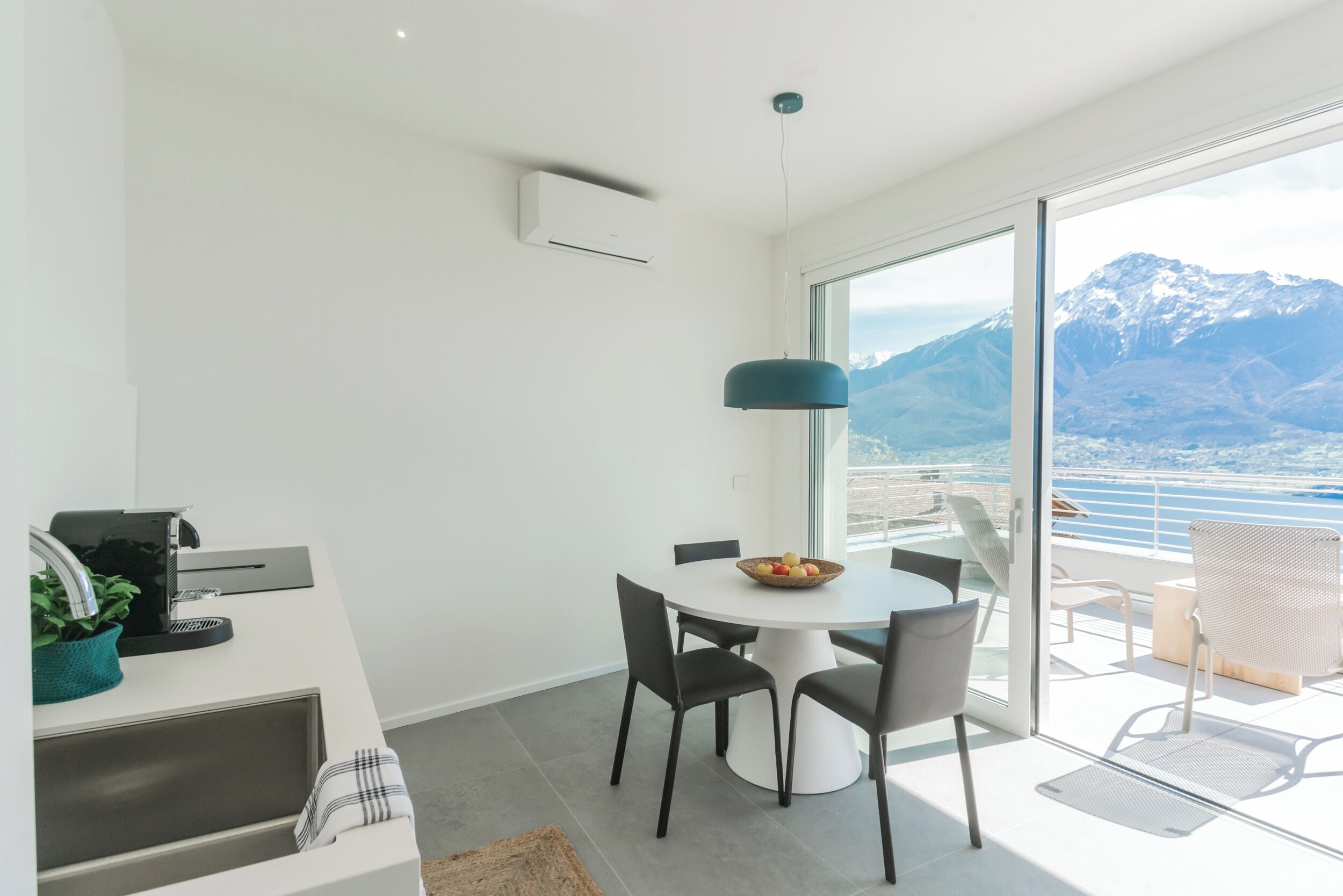 Un espace de salle à manger moderne, avec une table ronde, des chaises et une vue sur les montagnes grâce à de grandes fenêtres.