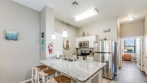 A modern kitchen with a granite island, stainless steel appliances, and a wooden floor.