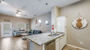 A modern kitchen with granite countertops, white cabinetry, and a built-in dishwasher.