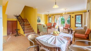 A spacious living area with a staircase, multiple seating arrangements, and a dining table set with a centerpiece. - 3+1 Villa with Sea View in Kalkan Center - Rose (Antalya)