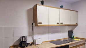 Une cuisine compacte équipée d’un four encastré, d’une machine à café, d’un grille-pain et d’un évier.