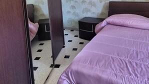 Een slaapkamer met een bed, nachtkastje, spiegel en hanglamp.