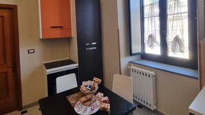 Een kleine kitchenette met een fornuis, oven en kastjes. Er is een raam met uitzicht op het omliggende landschap.