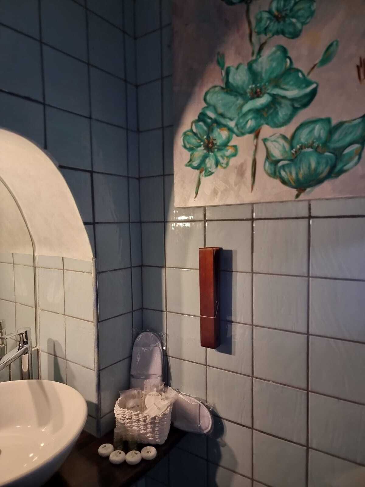 A bathroom with a white sink, a mirror, a towel rack, and a wall-mounted soap dispenser.