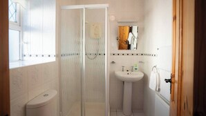 A bathroom with a glass shower enclosure, a pedestal sink, and a mirror above the sink.