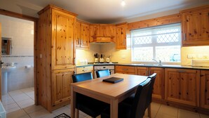 A kitchen with wooden cabinets, a dining table with chairs, and a window with a view.