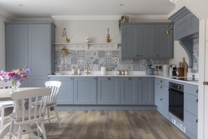 A kitchen with light blue cabinets, a white countertop, and a patterned backsplash.