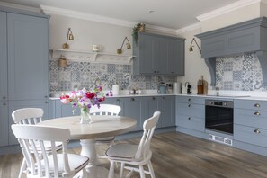 A modern kitchen with light blue cabinets, a white countertop, and a round dining table with chairs.