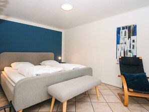 A bedroom with a bed, bench, and a painting on the wall.