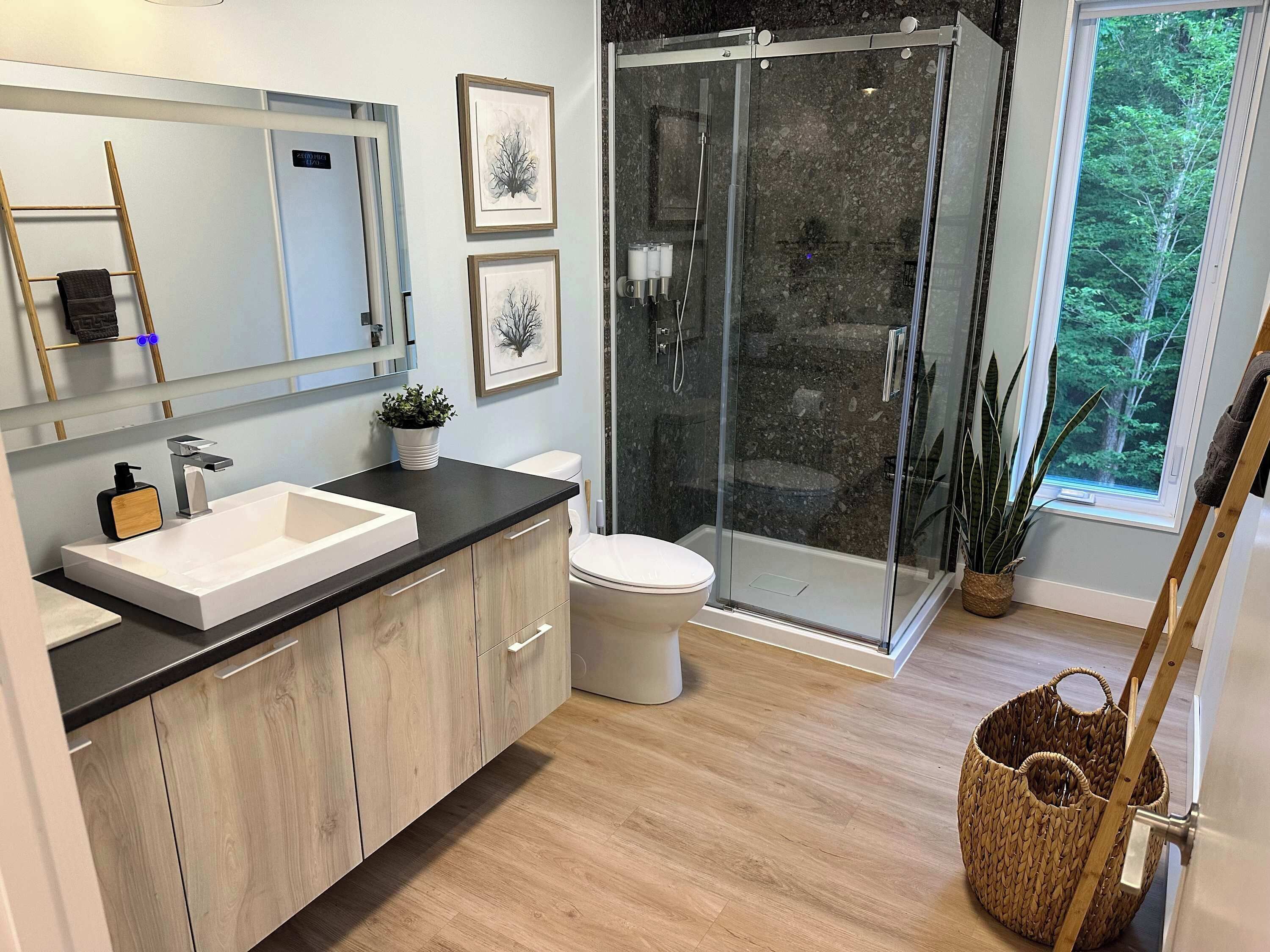 A modern bathroom with a large sink, toilet, and glass shower enclosure.