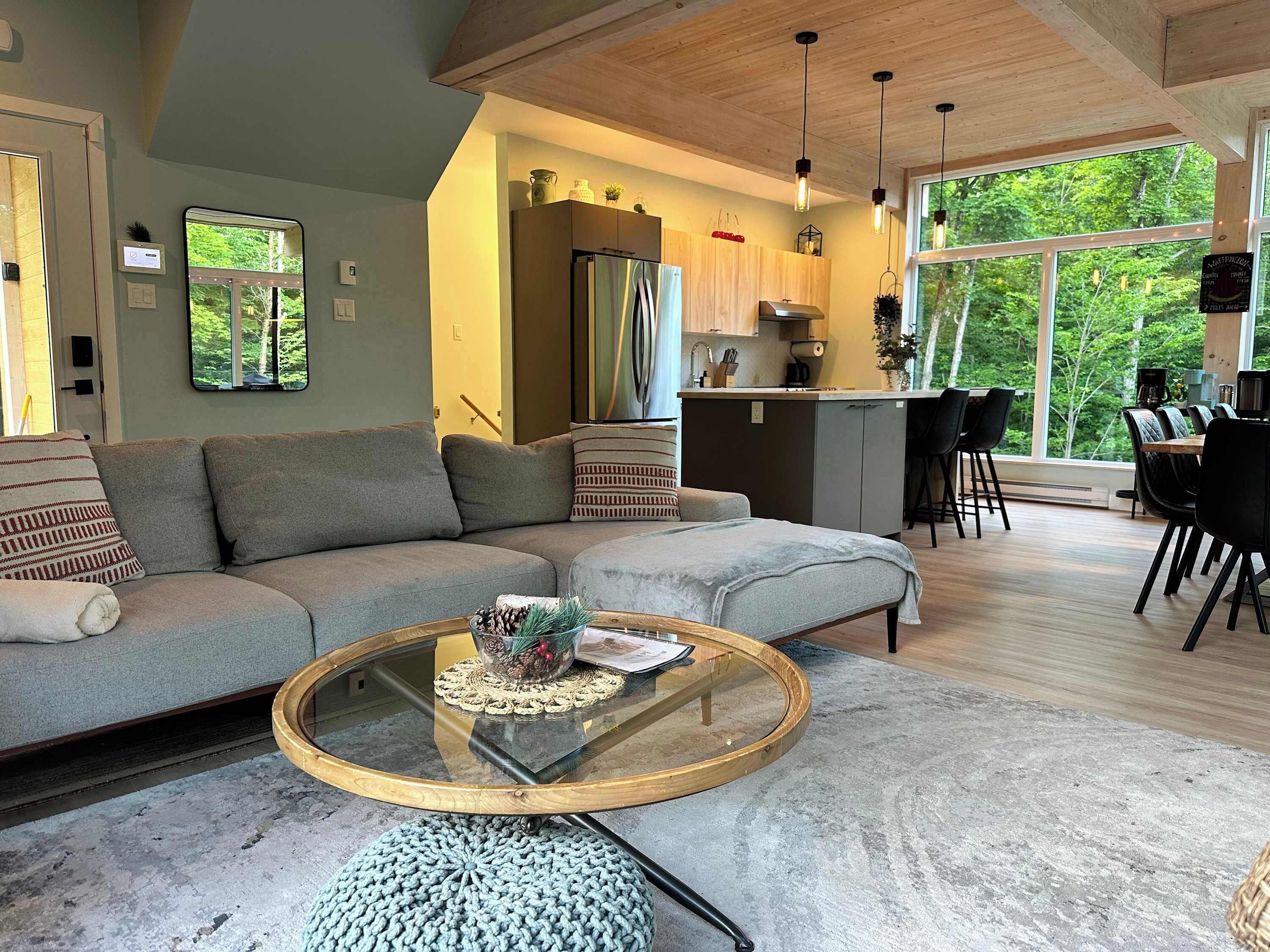 A modern living room with a sofa, a coffee table, and a view of the kitchen and dining area.