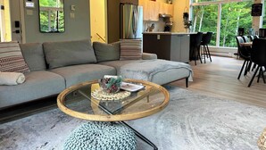 Ein modernes Wohnzimmer mit Sofa, Couchtisch und Blick auf die Küche und den Essbereich.