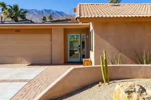 A residential building with a garage, a door, and a small garden with cacti.