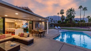 A modern outdoor living area with a pool, outdoor kitchen, and seating. - Maison Du Soleil – Luxury Palm Springs Retreat (Palm Springs)