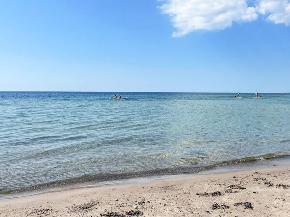 A beach with clear water, a sandy shore, and two paddleboarders in the distance. - 4 Star Holiday Home in Gotlands Tofta (Gotlands Tofta)