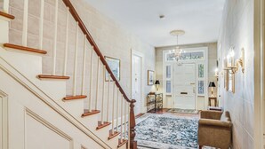 Una escalera con barandillas de madera, un tapete con diseño y una zona de estar con una silla.