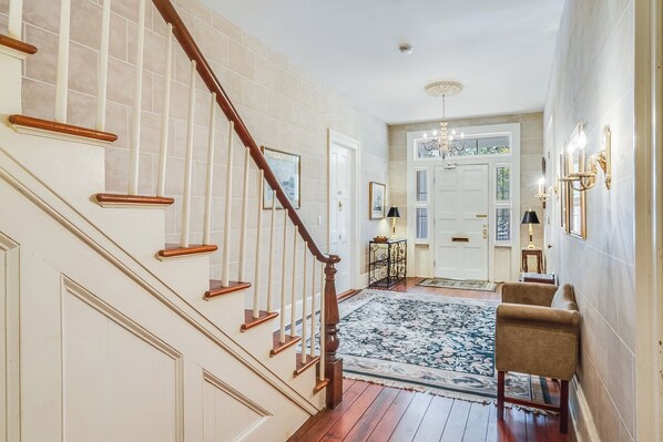 A staircase with wooden handrails, a patterned rug, and a seating area with a chair.