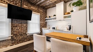Eine moderne Küche mit Backsteinwand, Holzboden und weißen Schränken.